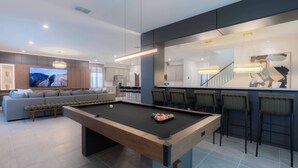 A modern living room with a pool table, a sofa, and a TV.