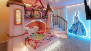 A bedroom with a castle-themed bed, a chandelier, and a Disney princess wall decoration.