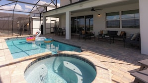 A swimming pool with a hot tub, lounge area, and outdoor seating.