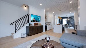 Een moderne woonkamer met een trap, een eethoek en een keuken.