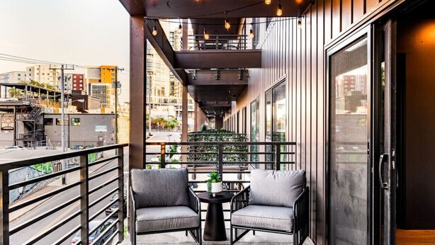 A balcony with two chairs, a small table, and a potted plant.