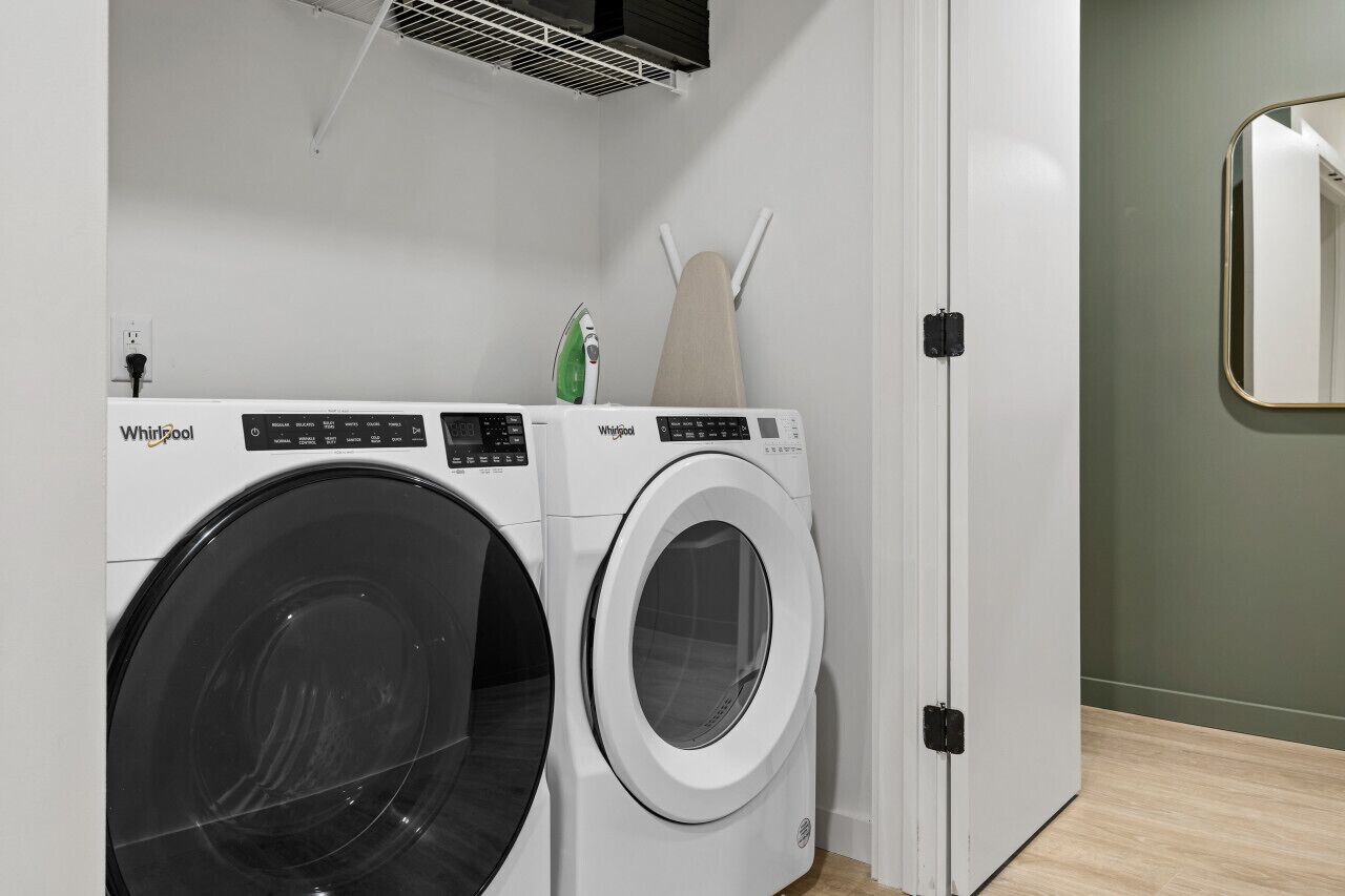 A Whirlpool washer and dryer in a room with a green wall and a wooden floor.