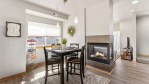 Un espace de repas moderne avec une cheminée, une table à manger avec des chaises et une vue sur l’extérieur.