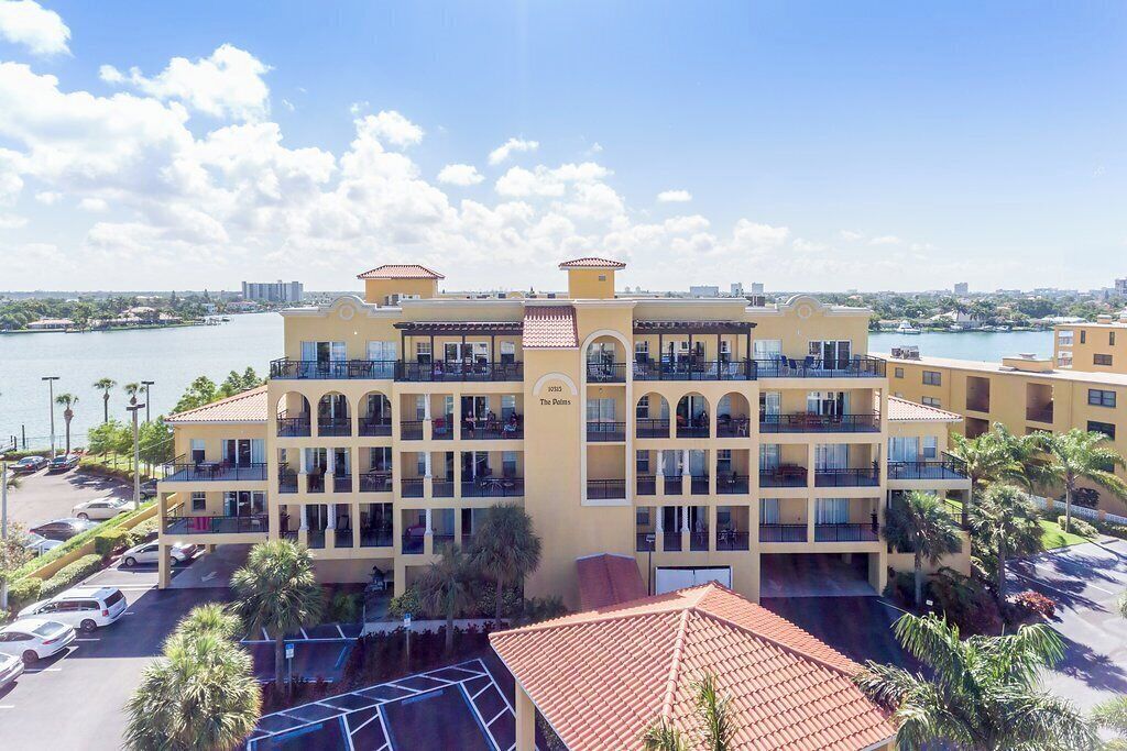 Un hôtel à plusieurs étages, doté de balcons, d’un parking et offrant une vue sur l’eau.
