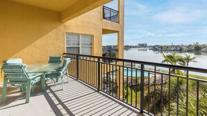 A balcony with a table and chairs, overlooking a lake and a cityscape.