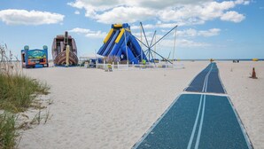 A beach with a blue slide, a ship-shaped play structure, and a clear sky.
