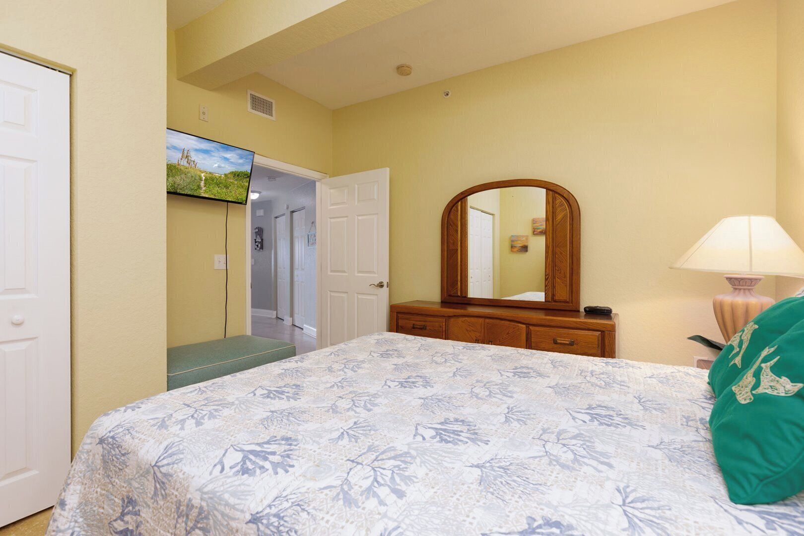 A bedroom with a bed, a dresser, a mirror, and a lamp.