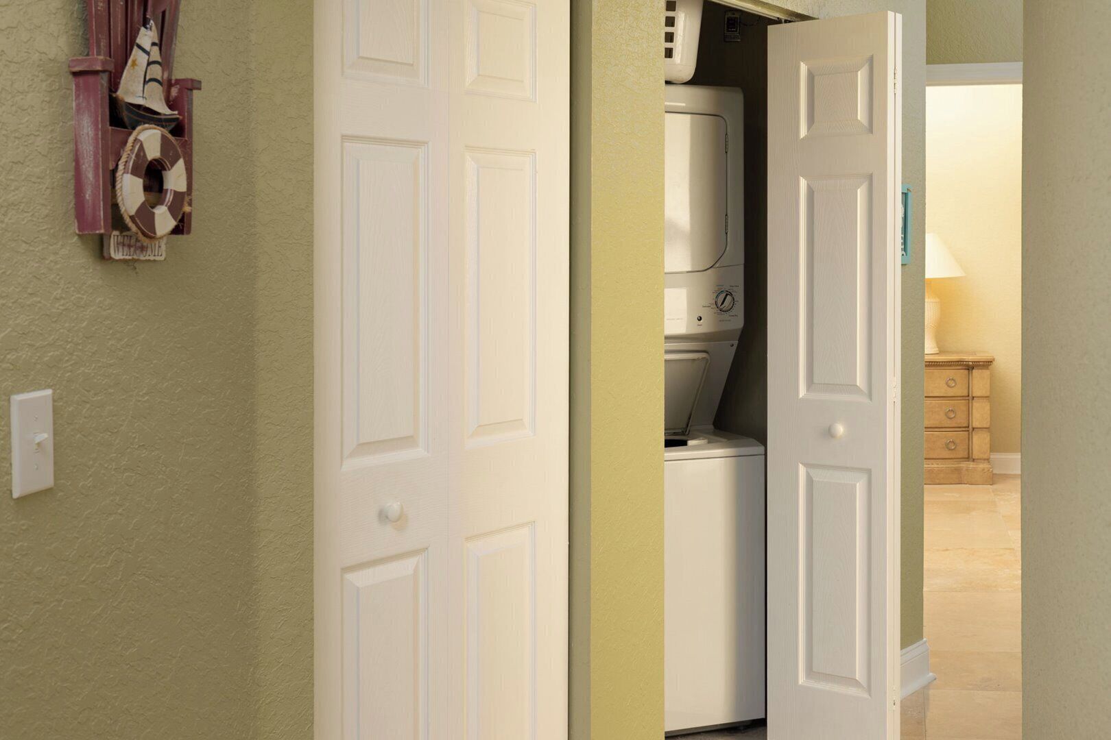 Un lavadero con lavadora y secadora, un armario pequeño y una puerta que da a otra habitación.