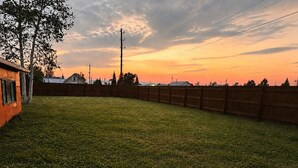 A fenced backyard with a grassy area and a wooden structure.