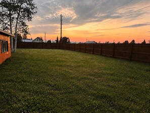A fenced backyard with a grassy area and a wooden structure.