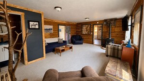 A cozy cabin interior with a sofa, armchair, and a fireplace.