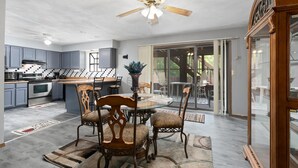 A modern kitchen with grey cabinets, a central island, and a dining area with a glass table and patterned chairs. - Touch of Class  3-bedroom townhome in Belleville King Bedroom. (Belleville)