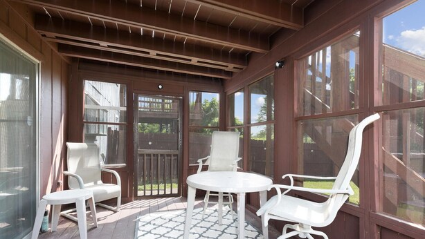 A covered patio with a table and chairs, large windows, and a wooden ceiling. - Touch of Class  3-bedroom townhome in Belleville King Bedroom. (Belleville)