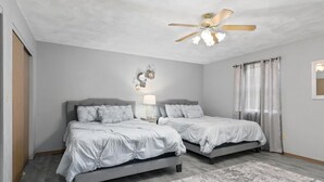 A bedroom with two beds, a ceiling fan, a nightstand, and a rug. - Touch of Class  3-bedroom townhome in Belleville King Bedroom. (Belleville)