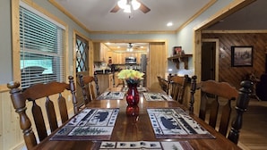 Une salle à manger avec une table en bois, des chaises et un vase de fleurs.