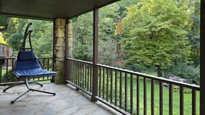 Une véranda avec une chaise bleue, des piliers en pierre et une vue sur un jardin luxuriant.