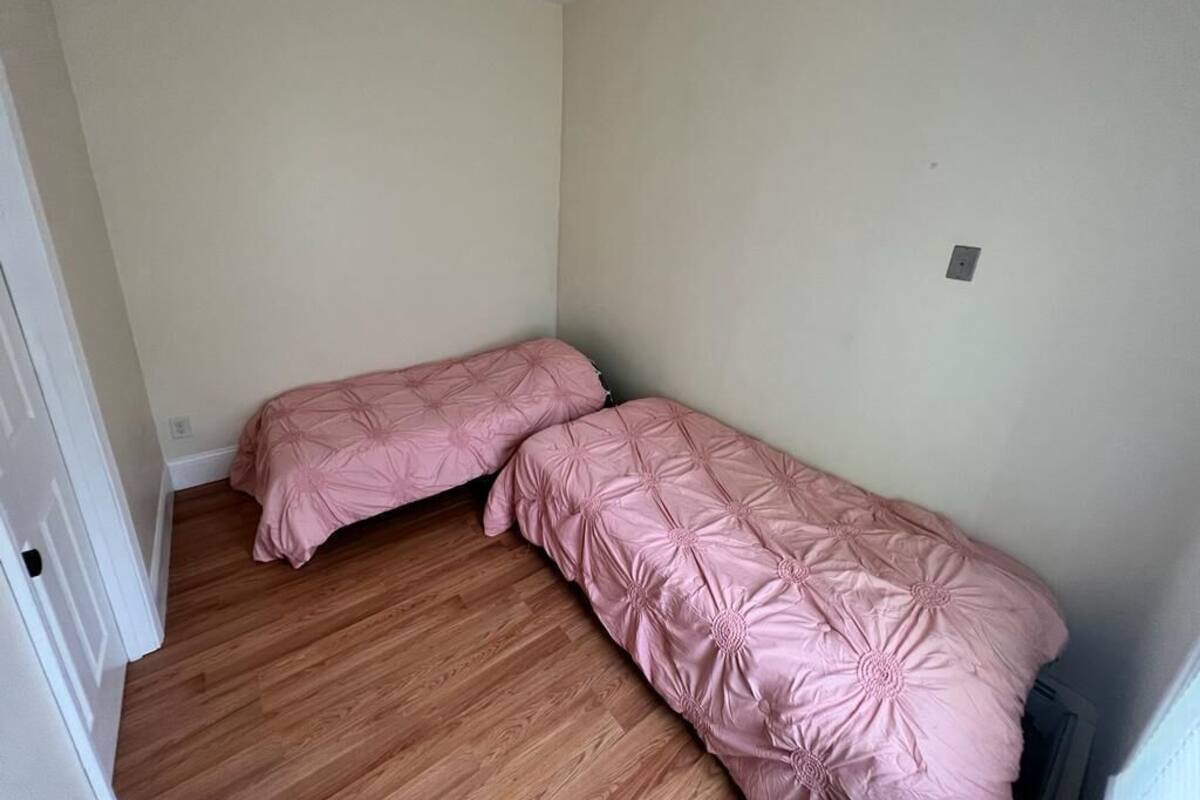 Una stanza piccola e semplice con due letti singoli, pavimento in legno e pareti spoglie.