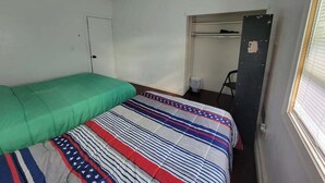 Ein kleiner, schlicht eingerichteter Raum mit einem Bett, einem Schrank und einem Fenster.