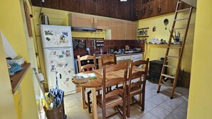 A kitchen with wooden cabinets, a white refrigerator, a wooden dining table with chairs, and a wooden ladder leaning against the wall. - Serene 2-bedroom chalet in Valjouffrey with stunning mountain views (Valjouffrey)