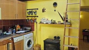 A kitchen with wooden cabinets, a washing machine, a stove, and a wooden dining table. - Serene 2-bedroom chalet in Valjouffrey with stunning mountain views (Valjouffrey)