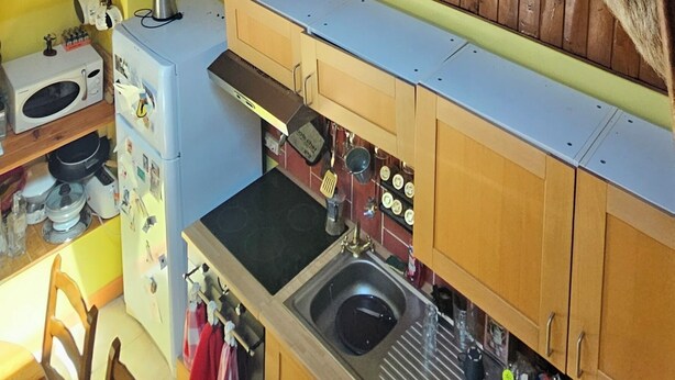 A kitchen with wooden cabinets, a sink, and a ceiling-mounted goat head sculpture. - Serene 2-bedroom chalet in Valjouffrey with stunning mountain views (Valjouffrey)