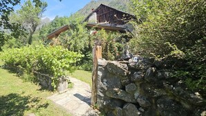 A rustic stone pathway leading to a wooden building with a stone wall and a wooden archway. - Serene 2-bedroom chalet in Valjouffrey with stunning mountain views (Valjouffrey)