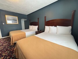 Habitación de hotel con dos camas individuales, una mesita de noche, una lámpara y un cuadro en la pared.