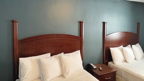 A hotel room with two wooden beds, white bedding, and a nightstand with a phone and remote control. - East Court Motel (Sarnia)