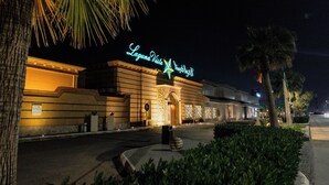 La façade d'un hôtel, illuminée par une enseigne au néon sur laquelle on peut lire « Laguna Vista Hotel & Resort », de nuit.