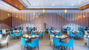Un restaurant moderne avec des chaises bleues et blanches, des tables en bois et des lambris en bois verticaux sur le mur.