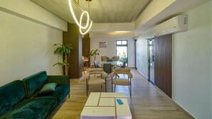 Un salon moderne avec un canapé vert, une table basse et un coin repas comprenant des chaises et une table.