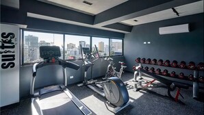 Une salle de sport moderne équipée de tapis de course, de vélos d’appartement et d’un mur rempli d’haltères.