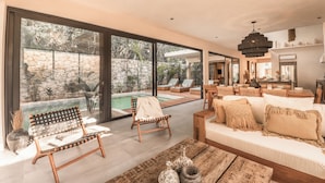 Amplia sala de estar con un gran ventanal, una piscina y un rincón de descanso con sofá y sillones.