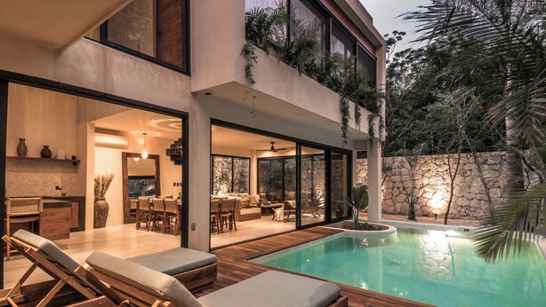 Una casa moderna con piscina, terraza de madera y zona de estar al aire libre.