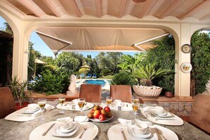 An outdoor dining area with tables set for a meal, a pool in the background, and lush greenery. - CAN JOSEP (MALDONADO), lovely villa in Pollença old town (Pollensa)