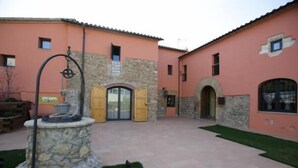 Un edificio con una fuente de piedra, una puerta de madera y un muro de piedra.