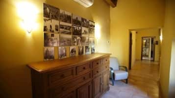 Un couloir avec une armoire en bois et des photographies accrochées au mur.