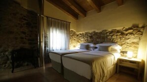 Un dormitorio con dos camas, paredes de piedra y techo de madera.