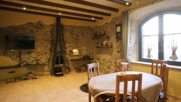 Una habitación rústica con paredes de piedra, chimenea, muebles de madera y televisor montado en la pared.