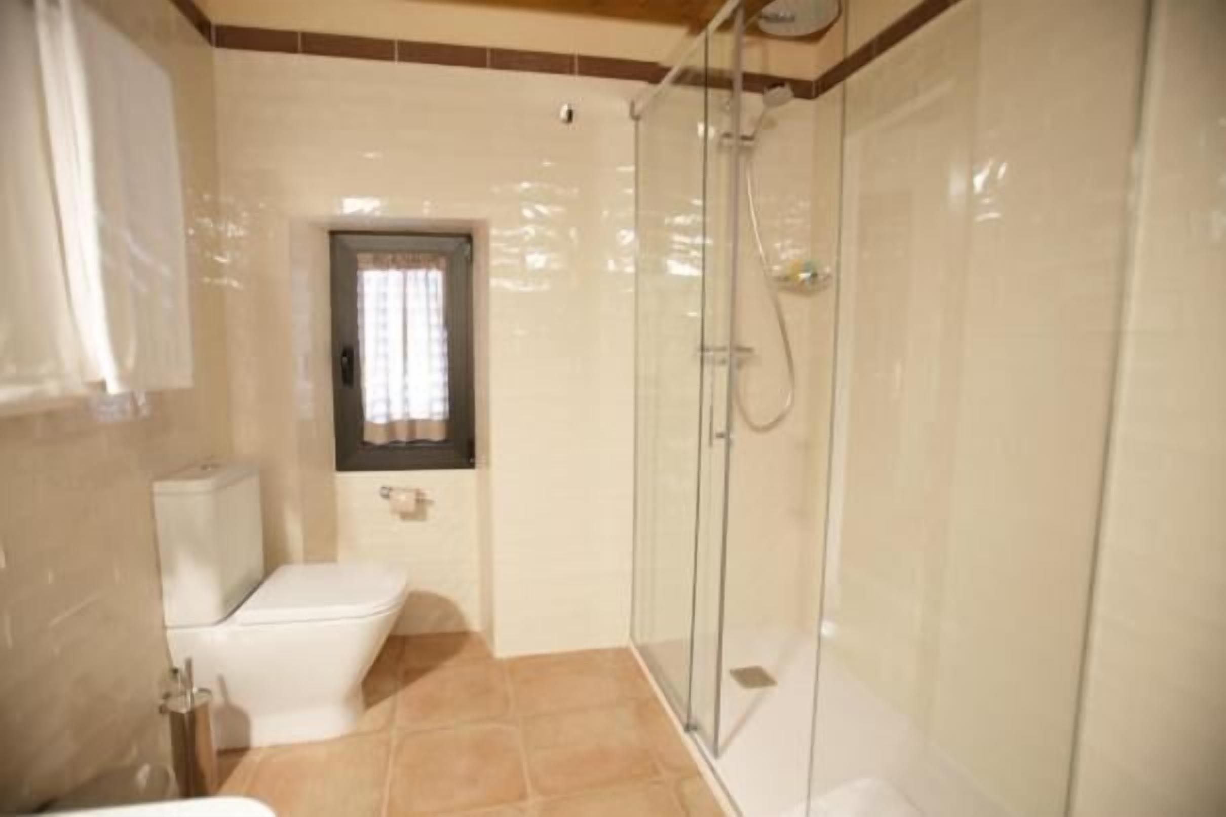 Un baño con inodoro, cabina de ducha y ventana.
