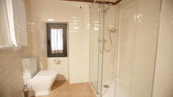 Un baño con inodoro, cabina de ducha y ventana.