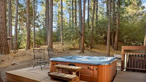 A hot tub on a wooden deck surrounded by trees.