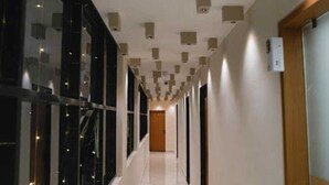 Un corridoio dal design moderno, con una parete in vetro su un lato e una porta in legno in fondo.