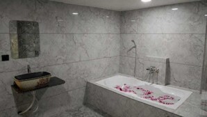 Un bagno moderno con un lavabo in marmo, una vasca freestanding e uno spazio doccia.