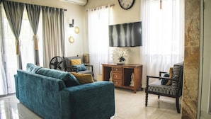 Una sala de estar con un sofá, una silla, un escritorio y un televisor.