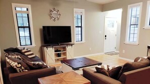 Uma sala de estar com um sofá, uma mesa de centro e uma televisão sobre um móvel.