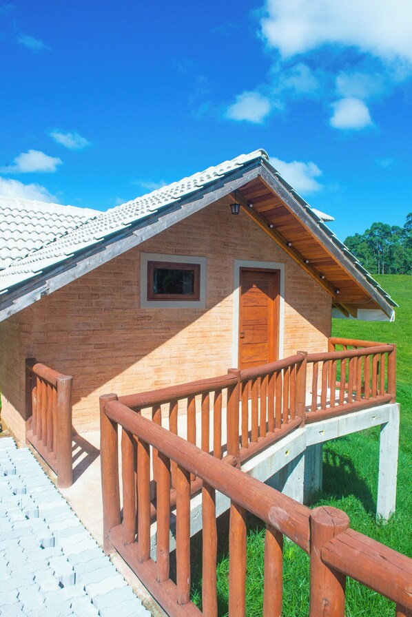 Une cabane en bois avec un balcon, une porte et une petite fenêtre.