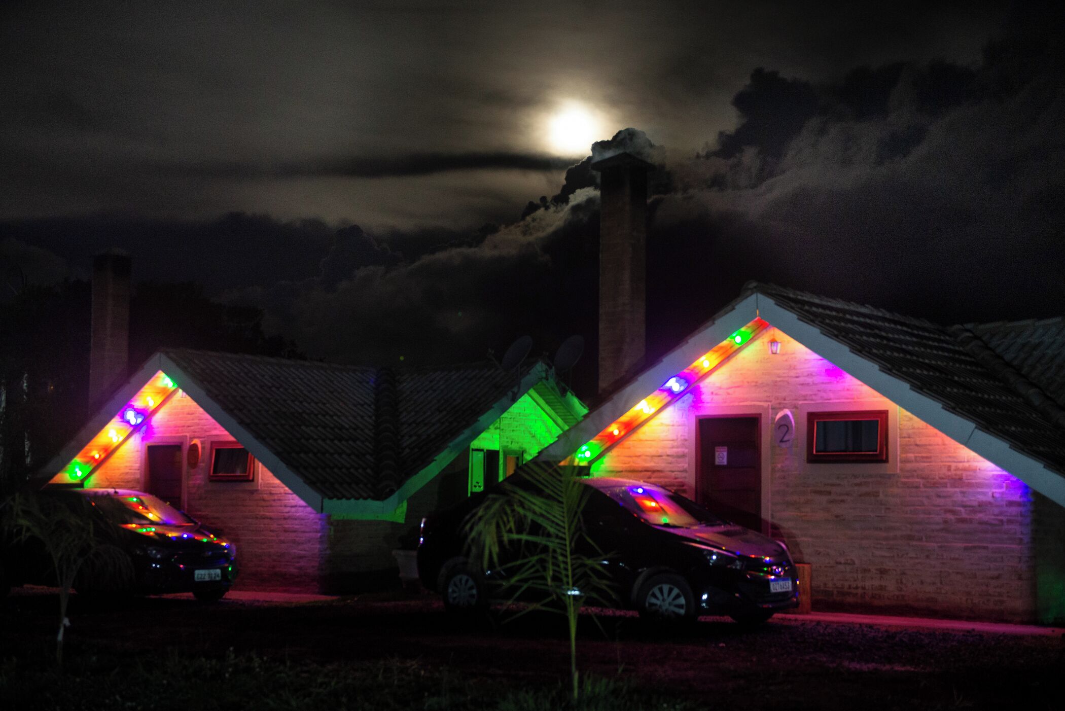 Two houses with colorful lights and a car parked in front.