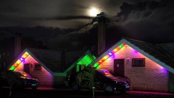 Two houses with colorful lights and a car parked in front.