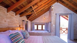 Ein Schlafzimmer mit einem großen Bett, Holzboden und Blick auf einen Balkon.